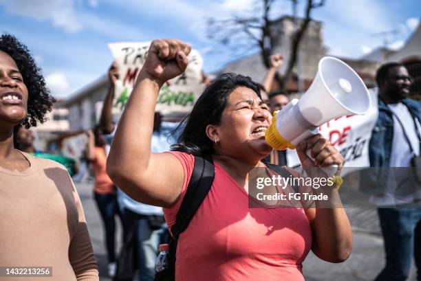 gruppe von menschen, die auf den straßen protestieren - soziale gerechtigkeit stock-fotos und bilder