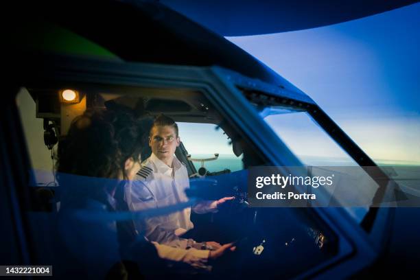 instructor explicando cómo funciona el simulador a un piloto en prácticas - simulador de vuelo fotografías e imágenes de stock