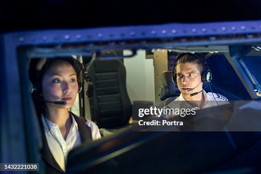 Instructor talking with trainee pilot sitting inside a flight simulator Instructor talking with trainee pilot sitting inside a flight simulator