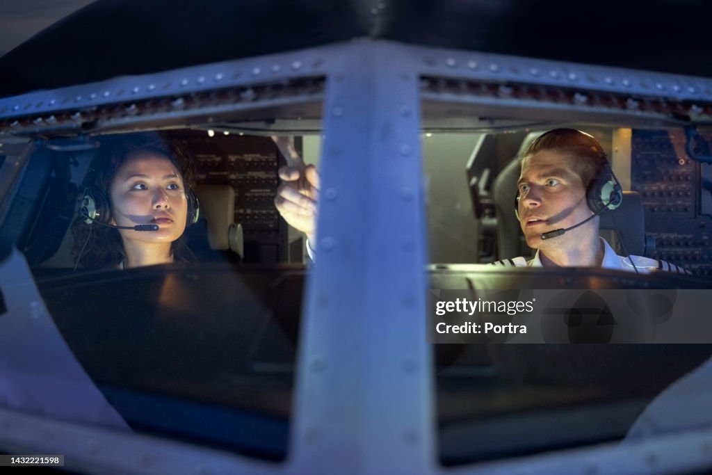 Pilot, der einer Schülerin beibringt, eine Ebene in einem Flugsimulator zu fliegen