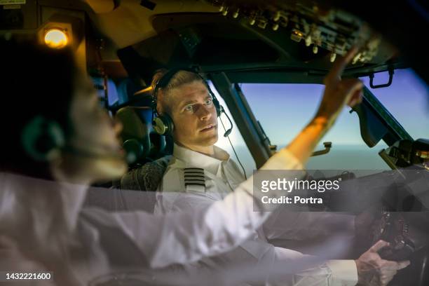 l'istruttore guarda l'apprendista pilota che regola gli interruttori durante l'addestramento al simulatore - navigator foto e immagini stock