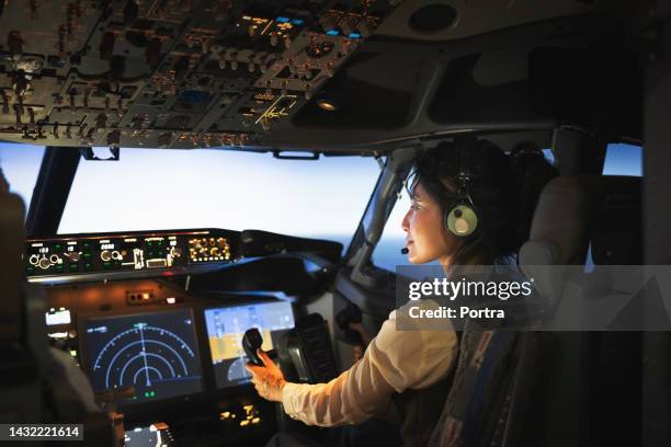 vista trasera de una mujer piloto volando un avión - pilotar fotografías e imágenes de stock