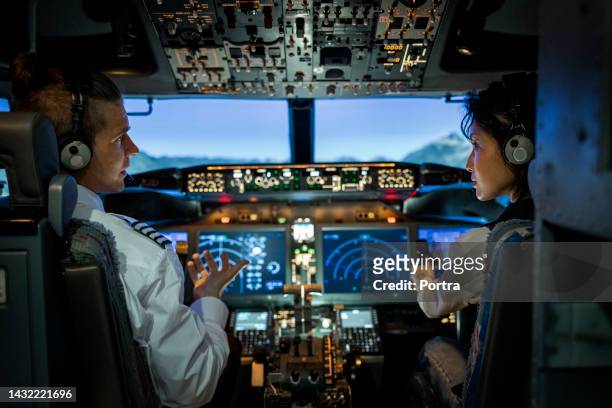 rear view of two pilots flying an commercial airplane jet - captains stock pictures, royalty-free photos & images