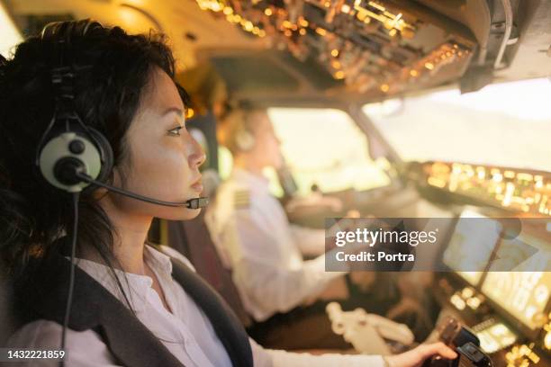 side view of a female pilot with male co-pilot flying an airplane - piloting stock pictures, royalty-free photos & images