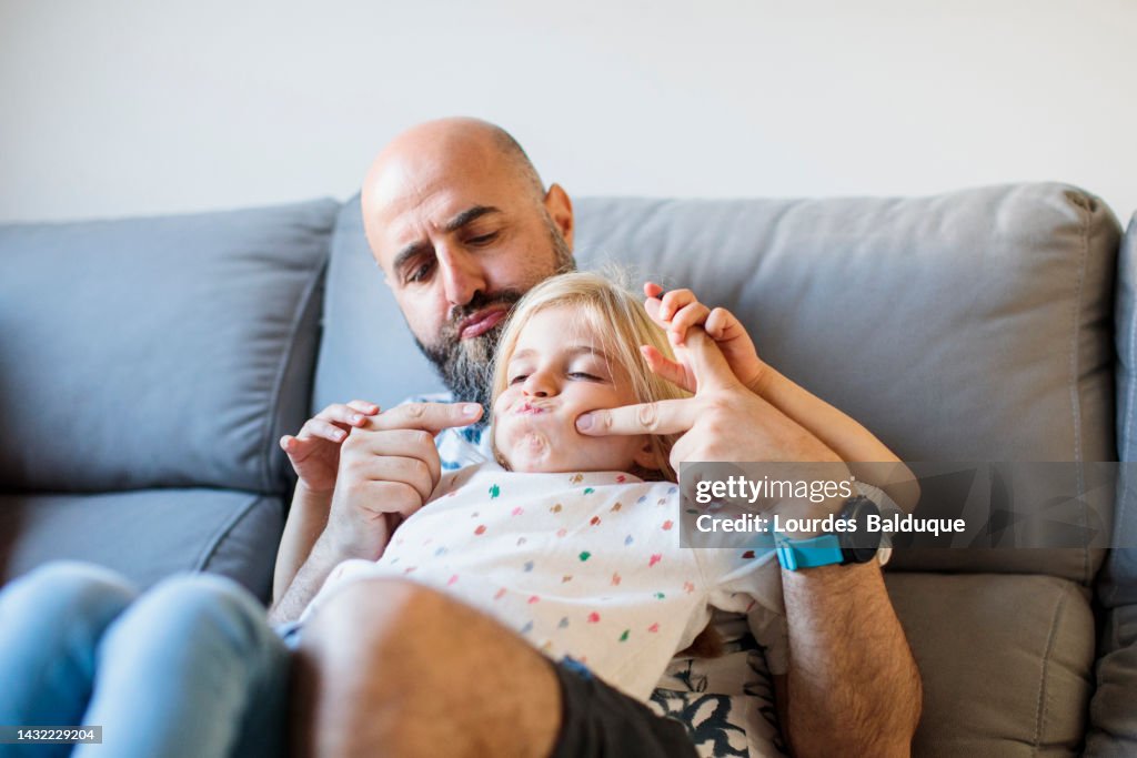 Father and daughter have fun playing on the sofa