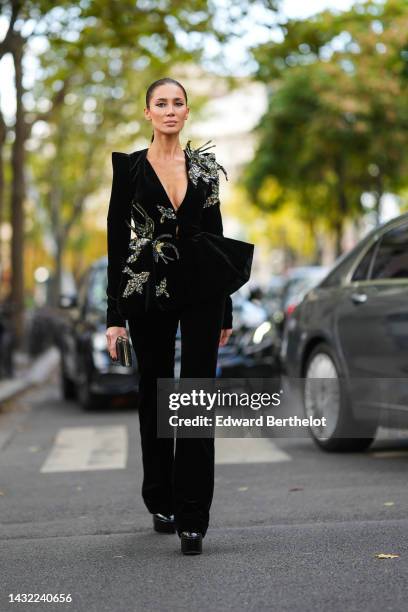 Sabina Jakubowicz wears a black velvet with embroidered gray / gold / blue embroidered sequined jewels / V-neck / shoulder-pads jacket, matching...