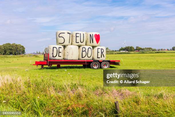 support the farmer letters on hay bales on trailer in meadow in the netherlands - nitrogen stock pictures, royalty-free photos & images