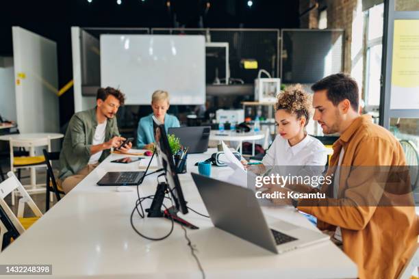 una mujer recién empleada está tomando algunas notas importantes mientras su colega comparte la información necesaria - web designer fotografías e imágenes de stock