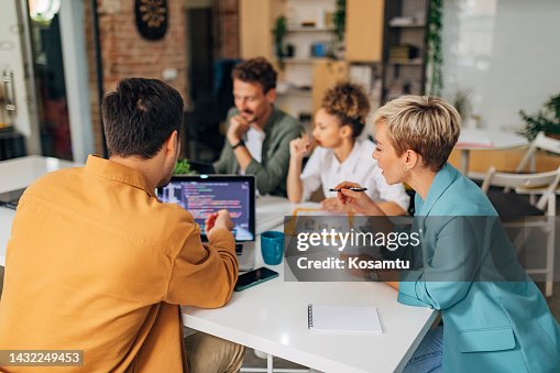 A male programmer shows a female colleague a coding technique. The codes are visible on the laptop screen A male programmer shows a female colleague a coding technique. The codes are visible on the laptop screen