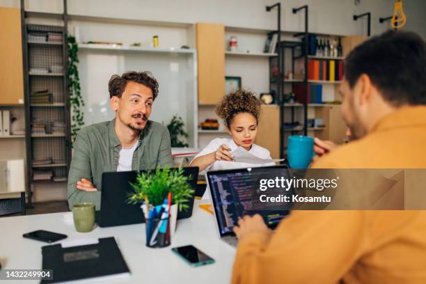 a hispanic woman and her friend are at a workshop where they learn how to code a program. an it expert explains the coding technique to them - html css stock pictures, royalty-free photos & images