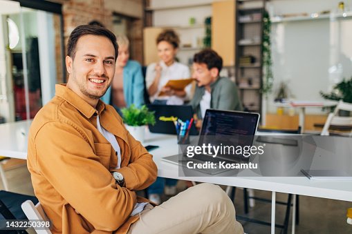 A cheerful male programmer is coding a program, while a group of his colleagues are working in a team and learning to code A cheerful male programmer is coding a program, while a group of his colleagues are working in a team and learning to code