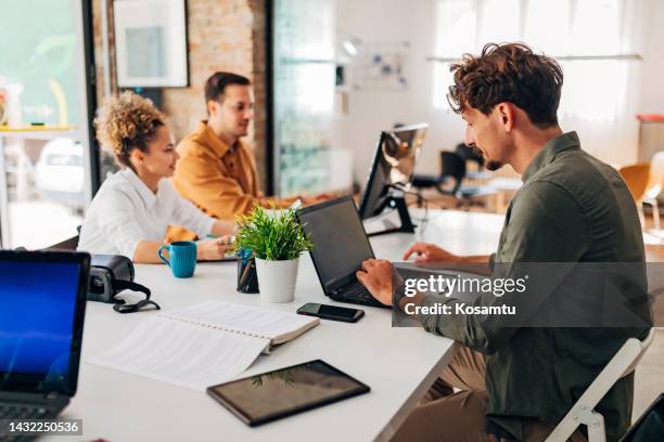 due uomini e una donna ispanica imparano a programmare programmi in ufficio - java foto e immagini stock