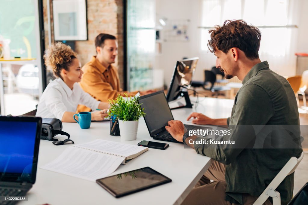 Two men and one Hispanic woman learn to code programs in the office