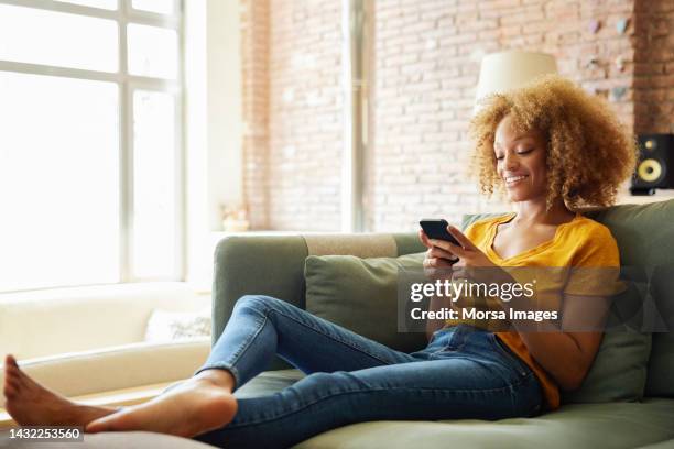 african american woman using social media on smart phone - smartphone couch stock pictures, royalty-free photos & images