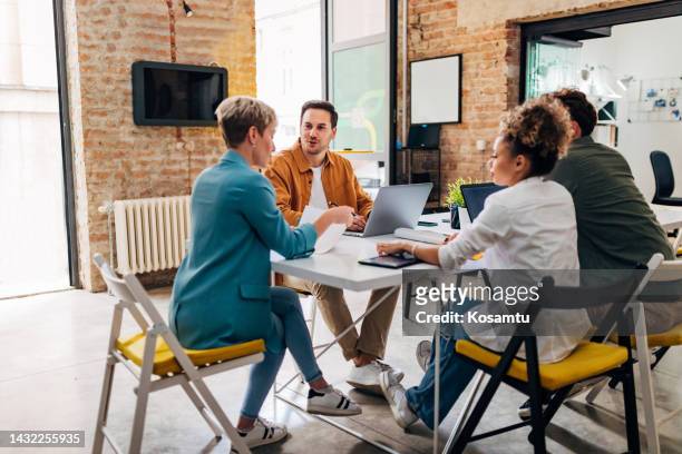 a small group of people talk to each other and discuss coding techniques - team talk stockfoto's en -beelden