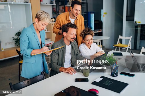 A small group of people discuss coding techniques while studying together in an office A small group of people discuss coding techniques while studying together in an office