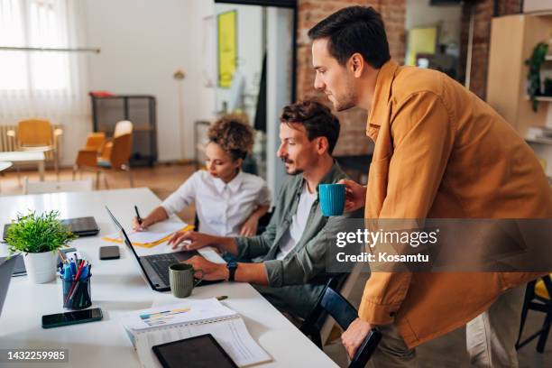 two students learn coding techniques using a laptop and take notes while being guided by an it expert - java stock pictures, royalty-free photos & images