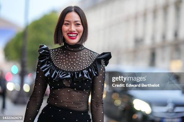 Tiffany Hsu wears a black tulle with embroidered white pearls long sleeves / midi dress with a black shiny varnished ruffled embroidered vanished...