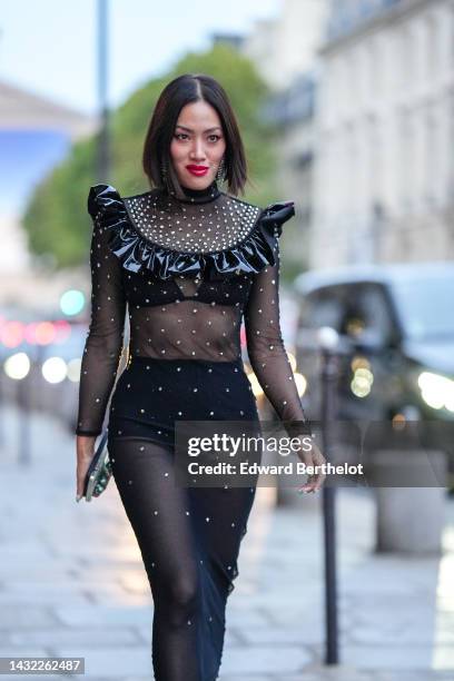 Tiffany Hsu wears a black tulle with embroidered white pearls long sleeves / midi dress with a black shiny varnished ruffled embroidered vanished...