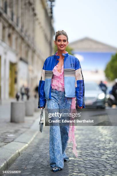 Emili Sindlev wears gold earrings, a pale pink and white tie and dye print pattern ruffled / embroidered rhinestones V-neck blouse with a long...