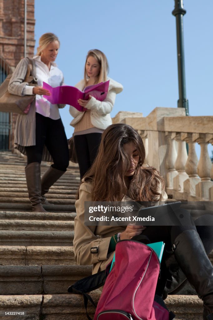 Teen girls use digital tablet/check work w teacher