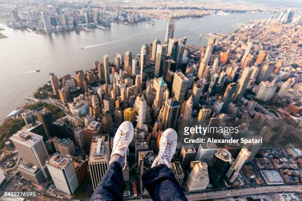 Tourist swinging his feet above Manhattan cityscape from helicopter, personal perspective view