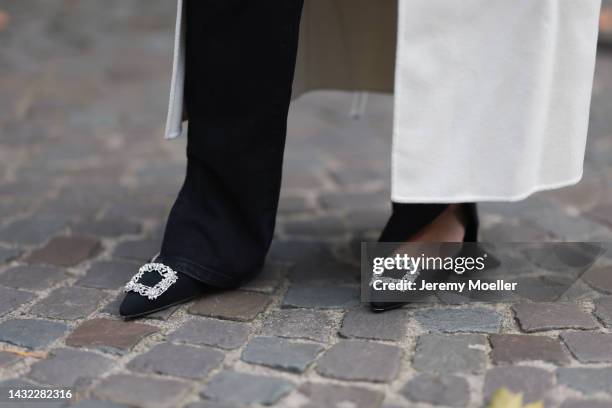 Milena Karl is seen wearing white wool Anine Bing long coat, black suit slit pants and black heels with glitter details, on October 08, 2022 in...