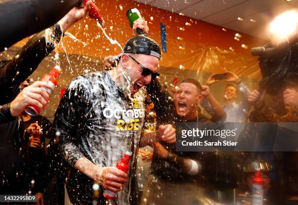 Joe Musgrove and Manny Machado of the San Diego Padres celebrate with their teammates in the locker room after defeating the New York Mets in game...