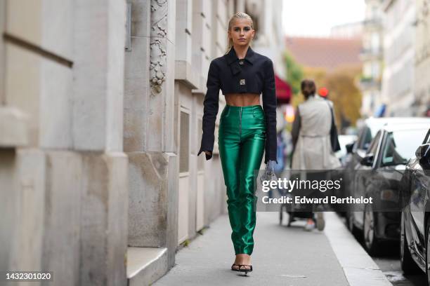 Caroline Daur wears a black cropped jacket with silver metallic buttoned, high waist green shiny zipper waist cigarette pants, a silver sequined...