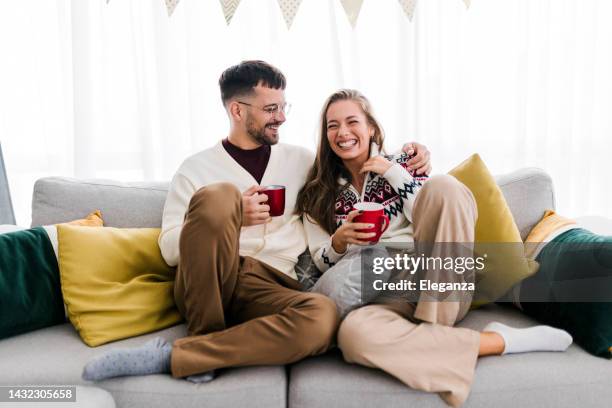 young couple celebrating new year at home - winter sofa stock pictures, royalty-free photos & images