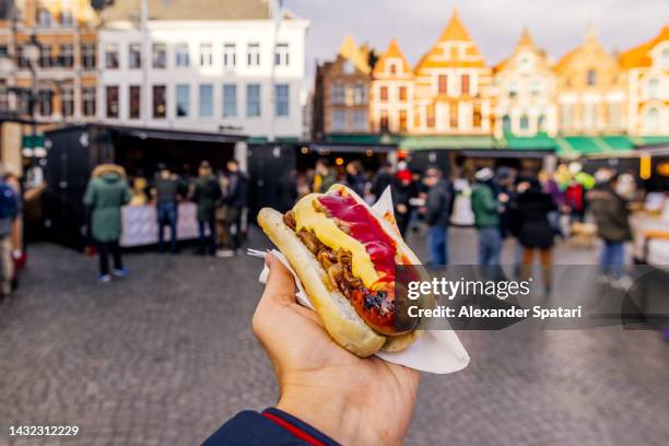 man eating sausage with bread and sauces at the christmas market in bruges, belgium - bbq winter photos et images de collection