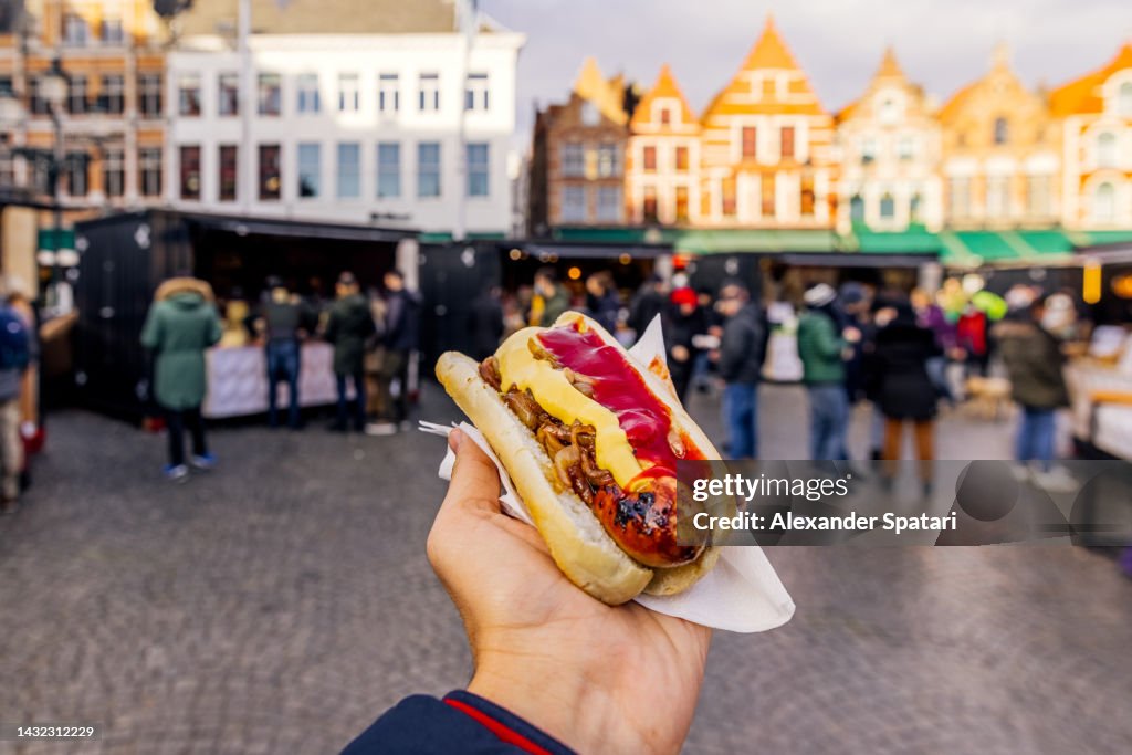 Man eating sausage with bread and sauces at the Christmas Market in Bruges, Belgium
