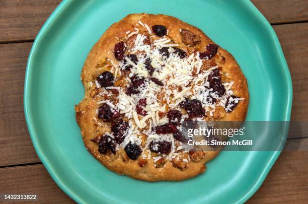 scone with dried cranberries, walnuts and dessicated coconut, on a plate on a wooden table - coconut biscuits stockfoto's en -beelden