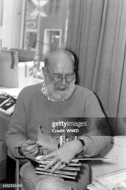 Writer Edward Gorey answers questions during an interview while signing his books.