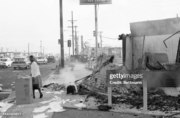 In the background is an overturned burned out car and a drive-in restaurant smoldering. It is a view of the aftermath of the rioting for a second...