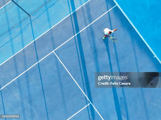 aerial view of a young adult playing tennis on a blue hard court. - spielfeld stock-fotos und bilder