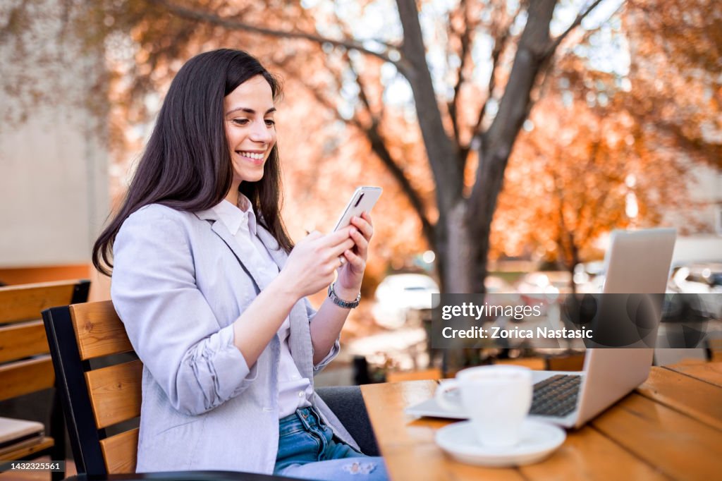Bebendo café usando laptop segurando telefone inteligente