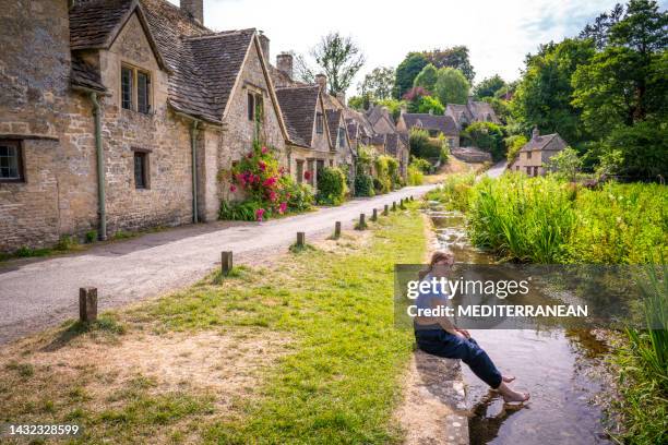 bibury, junge blonde touristenstudentin in arlington row in den england cotswolds uk - typisch englisch stock-fotos und bilder