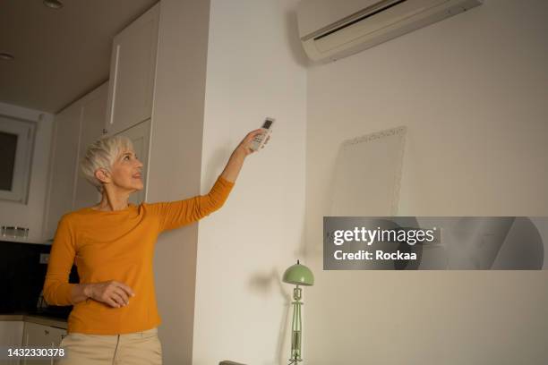 woman turning on air conditioner - air conditioner old stock pictures, royalty-free photos & images