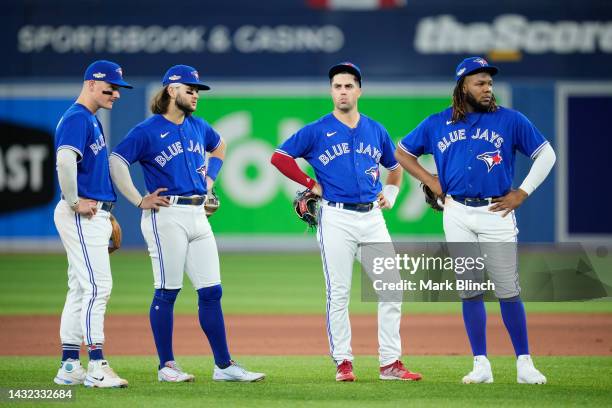 Matt Chapman, Bo Bichette, Whit Merrifield, and Vladimir Guerrero Jr. #27 of the Toronto Blue Jays stand on the field in a break against the Seattle...