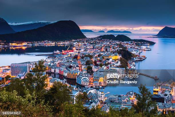 evening photo of alesund city in norway. beautiful night landscape with fjord. scandinavia. reflection of lamps on water. twilight in mountains - romsdal in norway stockfoto's en -beelden
