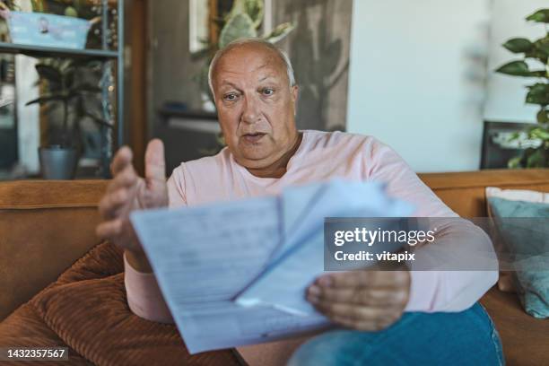 senior man looking at utility bill - bad news stock pictures, royalty-free photos & images