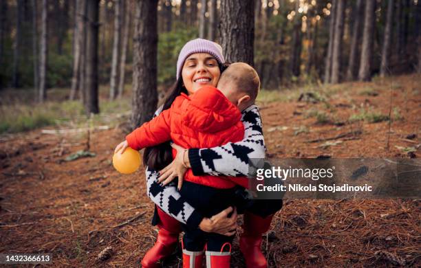 mother and her toddler son, enjoy the autumn day - oranje laars stockfoto's en -beelden