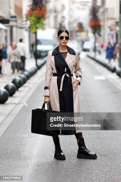 Model and artist Zoe Helali wearing a beige and black cashmere coat by Gobi Cashmere, a black butterfly net jumpsuit by Wolford, gold frame...