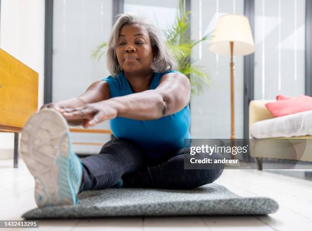 mujer madura haciendo ejercicio en casa - stretching fotografías e imágenes de stock