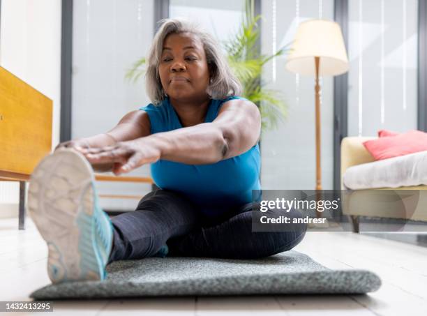 mature woman exercising at home - strekken stockfoto's en -beelden