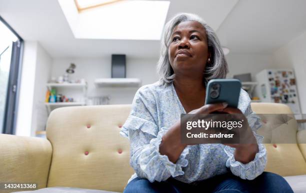 mature woman at home texting on her cell phone - middle aged woman at home stock pictures, royalty-free photos & images