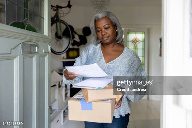 femme d’âge mûr à la maison recevant des colis et des lettres par la poste - boîte au lettre photos et images de collection