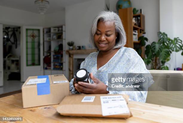 woman opening a subscription box at home - subscription stock pictures, royalty-free photos & images