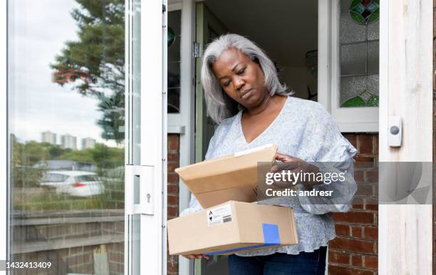 woman at home receiving some packages and looking confused - sending stock pictures, royalty-free photos & images